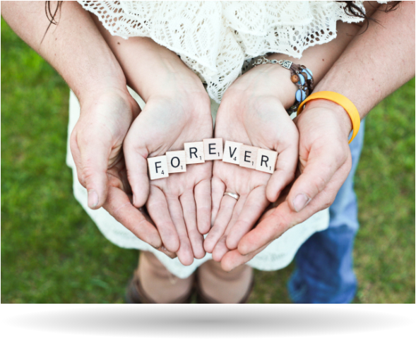 husband and wife hands holding game pieces that spell forever